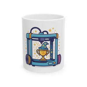 Könnte beinhalten: Ein weißer Keramikbecher mit einer bunten Grafik eines blauen 3D-Druckers. Im Inneren des Druckers trägt ein goldener Pokal einen blauen Zaubererhut mit gelben Sternen. Das Motiv ist von kleinen gelben Funken und bunten Konfettipunkten umgeben.