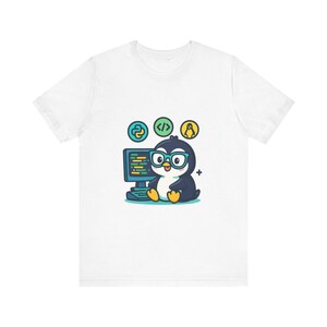 May include: A white t-shirt featuring a graphic of a cartoon penguin wearing teal glasses, sitting in front of a computer monitor. Above the penguin are three circular icons representing Python, code brackets, and a Linux penguin logo.