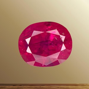 Könnte beinhalten: Ein leuchtender, oval geschliffener Rubin-Edelstein in einer tiefen, gesättigten roten Farbe mit sichtbaren inneren Einschlüssen und einer facettierten Oberfläche, die das Licht reflektiert und eine klassische, symmetrische Form mit scharfen Kanten zeigt.