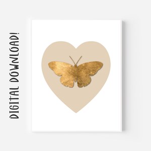 Puede incluir: Una silueta de mariposa dorada sobre una forma de corazón beige sobre un fondo blanco.