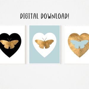 Puede incluir: Tres impresiones de arte de pared imprimibles que presentan una silueta de mariposa dorada dentro de una forma de corazón. Los corazones son negros, blancos y dorados.