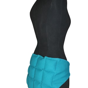 May include: Teal blue quilted fabric wrap with a contoured shape, designed to be worn around the waist.