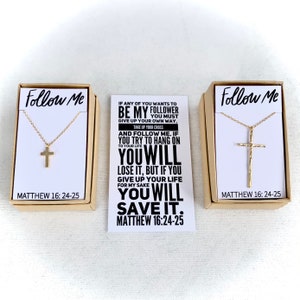 May include: Two boxes with gold cross necklaces inside. The boxes are brown and have the words "Follow Me" and "Matthew 16:24-25" printed on them. The card in the middle has a quote from the Bible: "If any of you wants to be my follower give up your own way, take up your cross and follow me. If you try to hang on to your life you will lose it, but if you give up your life for my sake you will save it. Matthew 16:24-25"