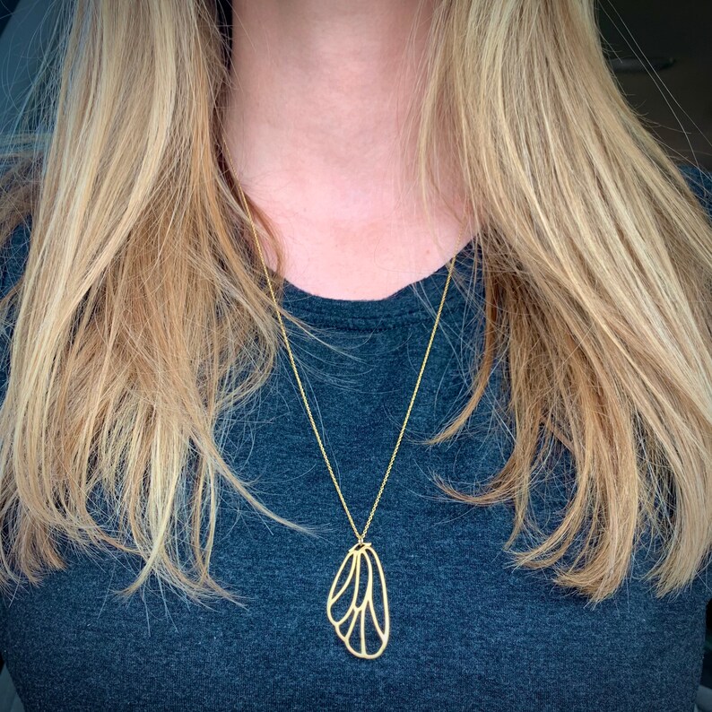 May include: A gold necklace with a delicate butterfly pendant. The pendant is made of thin metal and has a detailed design.