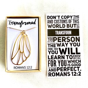 May include: Gold necklace with a butterfly wing pendant and a small box with the words "Transformed" and "Romans 12:2". A card with the text "Don't copy the behavior and customs of this world but let God transform you person the way you think. Then you will learn to know God's will for you which is good and pleasing and perfect. Romans 12:2" is also shown.