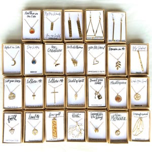 May include: A collection of 20 gold necklaces and earrings with various religious and inspirational quotes and scripture verses. Each piece is displayed in a small box with a white background and black text.