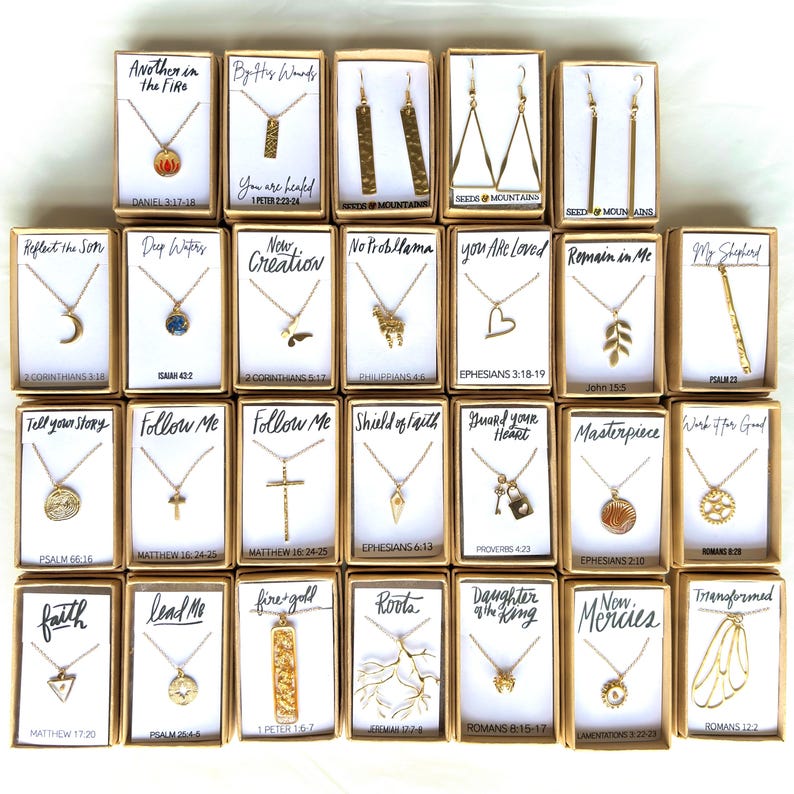 May include: A collection of 20 gold necklaces and earrings with various religious and inspirational quotes and scripture verses. Each piece is displayed in a small box with a white background and black text.