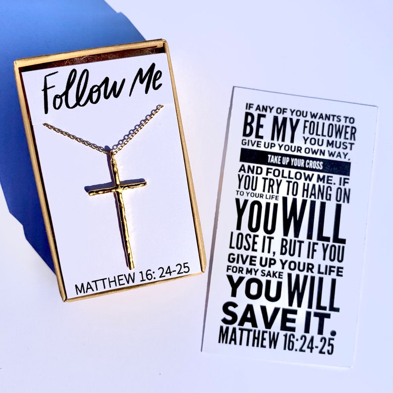 May include: A gold cross necklace in a box with the words "Follow Me" and "Matthew 16:24-25". The box is next to a card with the text "If any of you wants to be my follower you must give up your own way. Take up your cross and follow me. If you try to hang on to your life you will lose it, but if you give up your life for my sake you will save it. Matthew 16:24-25"