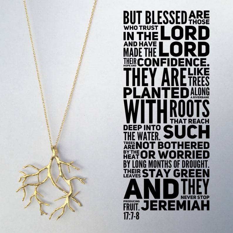 May include: A gold necklace with a tree branch pendant. The necklace is hanging against a white background with a black and white text overlay that reads "But blessed are those who trust in the Lord and have made the Lord their confidence. They are like trees planted along a riverbank with roots that reach deep into the water. Such trees are not bothered by the heat or worried by long months of drought. Their leaves stay green and they never stop producing fruit. Jeremiah 17:7-8"