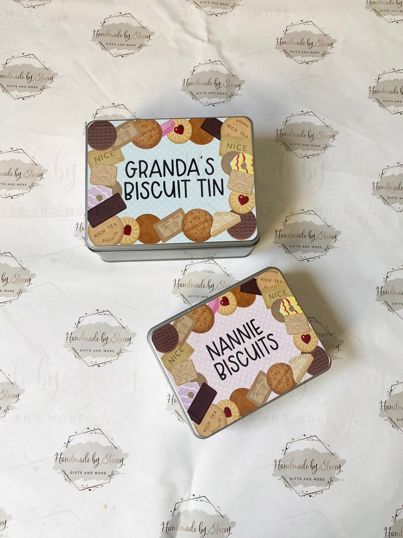 May include: Two metal biscuit tins with colorful designs. The top tin says "GRANDA'S BISCUIT TIN" and the bottom tin says "NANNIE BISCUITS". Both tins feature a variety of biscuits and the text "RICH TEA" and "NICE".