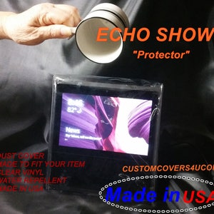 May include: Clear plastic cover for an Echo Show smart display. The cover is labeled "Echo Show "Protector"" and "Made in USA".