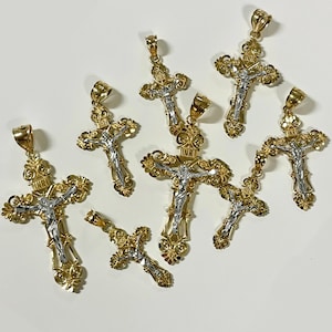 Puede incluir: Ocho colgantes de crucifijo en tono dorado y plateado con dise&ntilde;os intrincados. Los colgantes presentan una figura de Jesucristo en una cruz con la inscripci&oacute;n "INRI" arriba.
