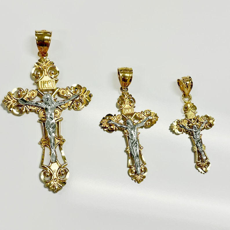 Puede incluir: Tres colgantes de crucifijo de oro y plata de diferentes tama&ntilde;os. El colgante m&aacute;s grande presenta un dise&ntilde;o detallado con una figura de Jesucristo.