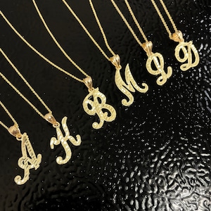 May include: A set of gold necklaces with initial pendants. The pendants are in a cursive script font and are arranged in alphabetical order from A to D.