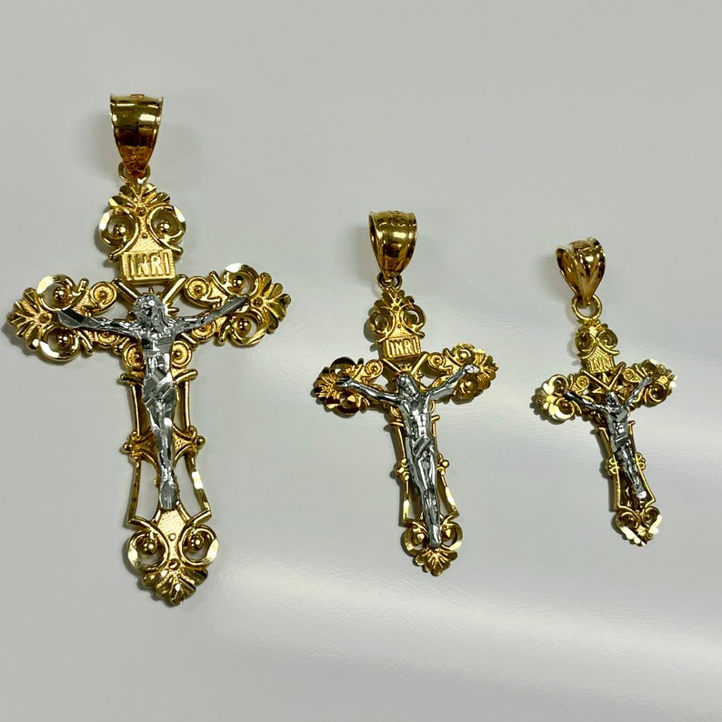 Puede incluir: Tres colgantes de crucifijo de oro y plata de diferentes tama&ntilde;os. Los crucifijos presentan un dise&ntilde;o detallado con adornos ornamentados y una figura de Jes&uacute;s de plata.
