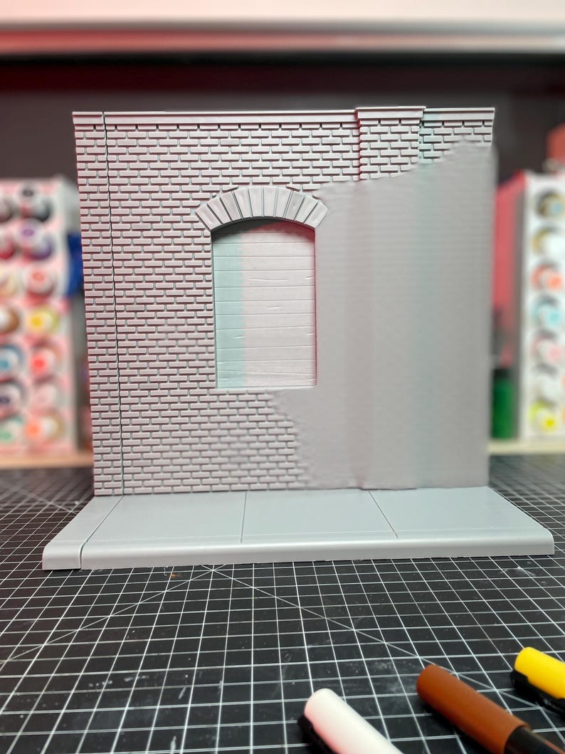 May include: A gray brick wall with a window and a sidewalk. The wall is made of a textured material and has a realistic look. The window is arched and has a gray frame. The sidewalk is made of concrete and has a smooth surface.