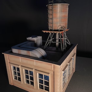 May include: A miniature model of a building with a water tower on the roof. The building is made of wood and painted a light brown color. The water tower is made of metal and painted a rusty brown color. The building has windows on the front and sides.