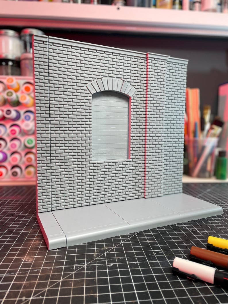 May include: A gray brick wall with a gray arched doorway and a gray sidewalk. The wall is made of small bricks and has a rough texture. The doorway is arched and has a gray door. The sidewalk is made of concrete and has a smooth texture.