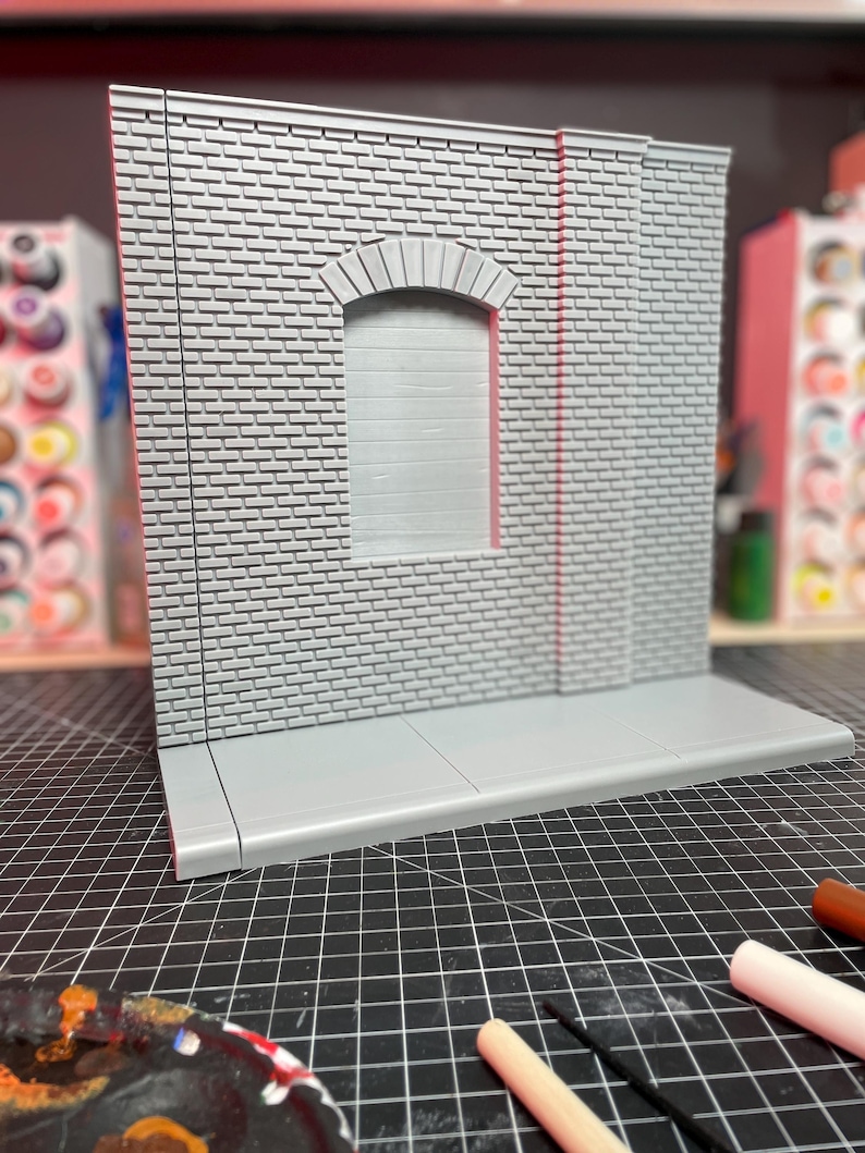 May include: A gray brick wall with a window and a sidewalk. The wall is made of small bricks and has a rough texture. The window is arched and has a white frame. The sidewalk is made of concrete and has a smooth surface.