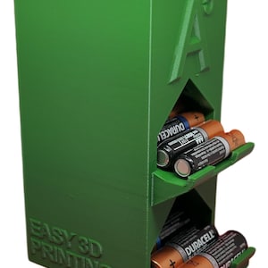 May include: Green 3D printed battery organiser with slots for AA batteries. The organiser has the text "EASY 3D PRINTING" and "A5" on the front.