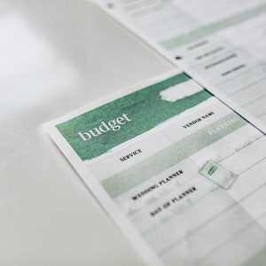 May include: A white budget planner with a green watercolor design. The planner has sections for service, vendor name, and planning.