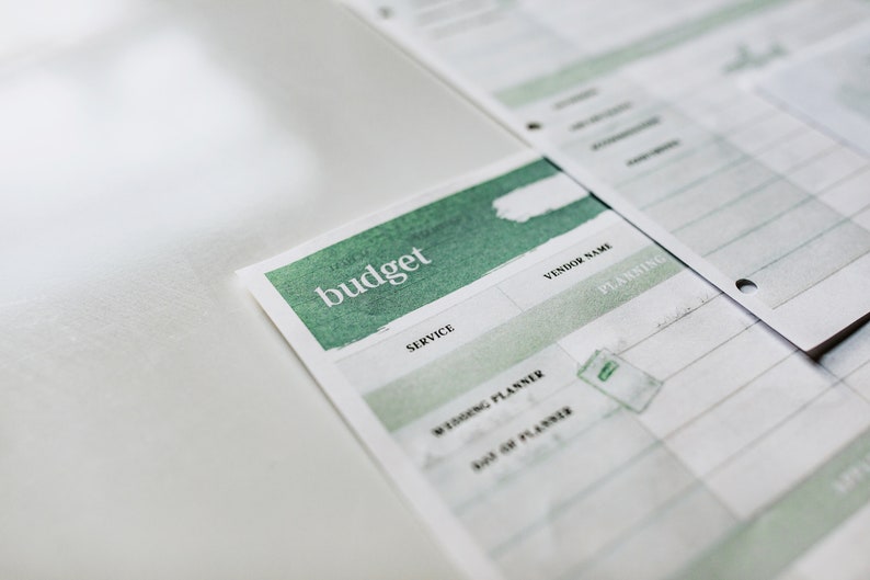 May include: A white budget planner with a green watercolor design. The planner has sections for service, vendor name, and planning.