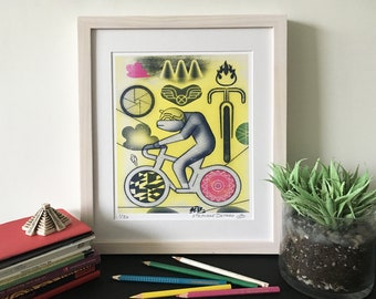 May include: A yellow and black print of a person riding a bicycle with a pink and black wheel. The print is framed in a light wood frame and has the text "1/50" and "STEPHANE DETROUX" in the bottom right corner.
