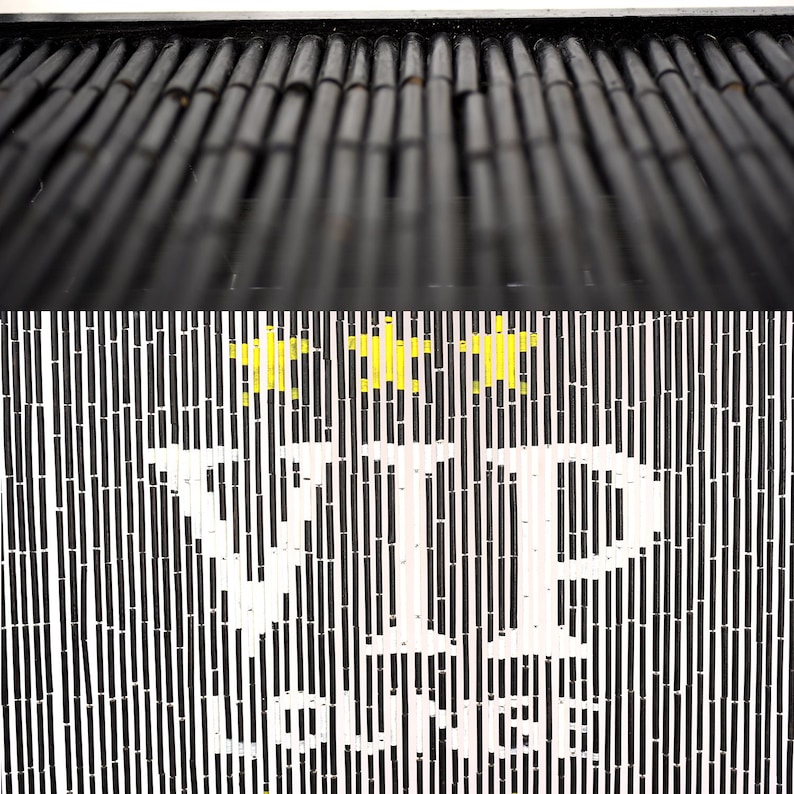 May include: A black and white striped sign with the words "VIP LOUNGE" in large white letters. Above the text are three yellow star shapes. The top of the sign has a series of black bamboo poles.