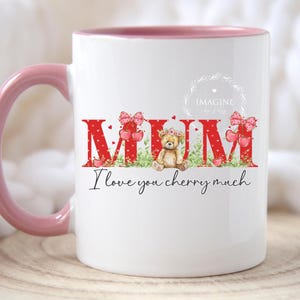 May include: White ceramic mug with a pink rim. The mug features a red, white and green design with the word "MUM" in large letters and a teddy bear. The text "I love you cherry much" is printed below the design.