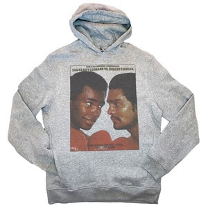 May include: Gray hooded sweatshirt with a vintage-style print of Sugar Ray Leonard and Roberto Duran facing each other in a boxing match. The text "World Welterweight Championship" and "Sugar Ray Leonard vs. Roberto Duran" is printed above the image.