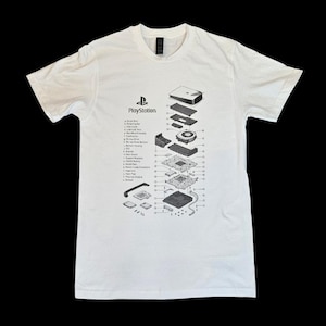 May include: White t-shirt with a detailed diagram of a PlayStation console's internal components. The design includes the PlayStation logo and labels for each part. A classic tee for gamers.