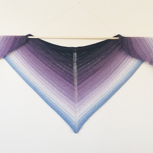 May include: A triangular knitted shawl with a gradient of colors from dark purple to light blue.