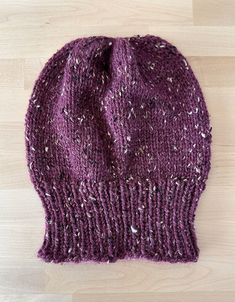 May include: A burgundy knitted beanie with white flecks throughout.
