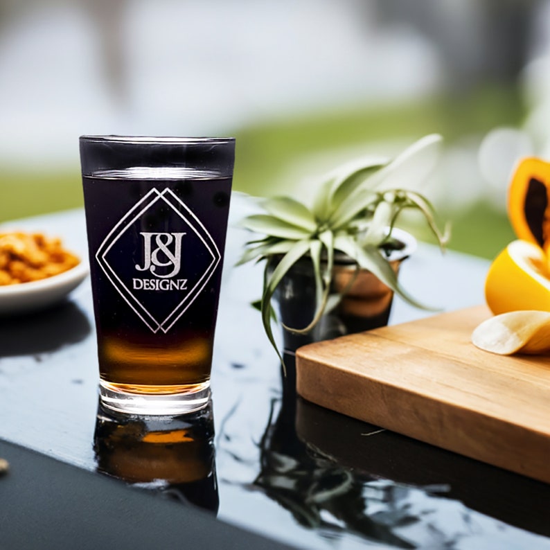 Custom laser-etched Libbey 16 oz pint glass with intricate logo, showcasing personalized drinkware for events and gifts