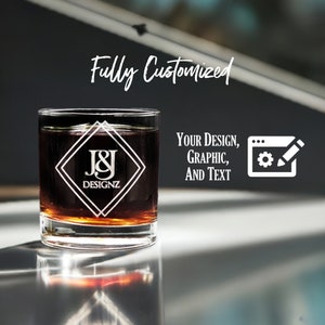 Customized 11 oz Libbey heavy base rocks glass with intricate etched logo and text design, showcasing personalization options for corporate branding or individual style on a reflective surface.