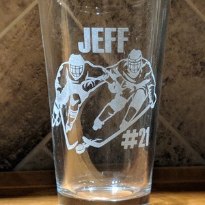 Personalized 16 oz pint glass etched with custom hockey player design and the name 'JEFF' with jersey number #21, perfect for sports fans, coaches and unique gifts, showcasing precision laser engraving on clear glass.