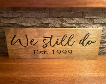 Puede incluir: Un letrero de madera con el texto "We still do" y "Est. 1999" en letras negras.