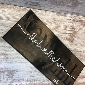 May include: A dark brown wooden sign with the text "Connell & Madison est 2021" in white lettering. The sign has a distressed look and is perfect for a rustic home decor style.