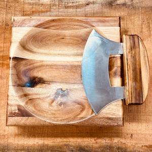 Op de afbeelding: Een houten serveerschaal met een ingebouwde gebogen kom en een gebogen mes dat aan de zijkant is bevestigd.