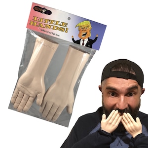 Puede incluir: Un par de manos de goma de color carne de aspecto realista en una bolsa de plástico transparente. La bolsa tiene una etiqueta que dice "Asylum Toys Little Hands! Includes Left and Right Hands". En la etiqueta hay una imagen de dibujos animados de un hombre con corbata roja y traje azul. Una persona está sosteniendo las manos frente a su cara, cubriéndose la boca.