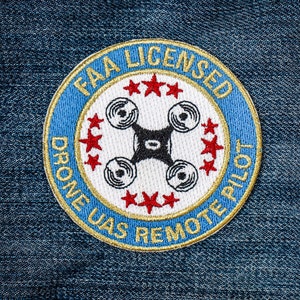 May include: A blue and gold embroidered patch with the text "FAA Licensed Drone UAS Remote Pilot" and a stylized image of a drone with five red stars.