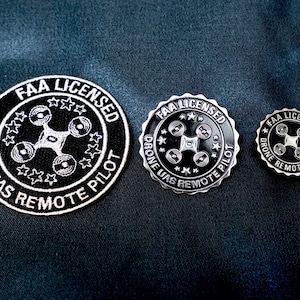 May include: Three FAA Licensed Drone UAS Remote Pilot badges. The largest badge is a black and white embroidered patch. The two smaller badges are silver metal pins. All three badges feature a drone icon and the text "FAA Licensed Drone UAS Remote Pilot".