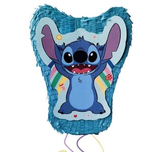 May include: A blue piñata shaped like the character Stitch from the Disney movie Lilo & Stitch. The piñata features a blue Stitch graphic with a rainbow and is decorated with blue fringe and hanging strings.