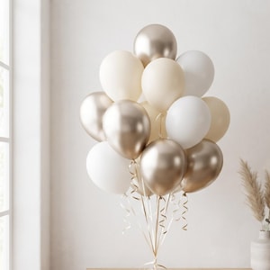 Puede incluir: Un racimo de globos en tonos dorado metálico, crema mate y blanco sólido. Los globos están atados con cintas finas y rizadas que se extienden hacia abajo desde la base del arreglo, creando una composición decorativa.