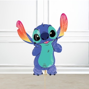 May include: A blue Stitch character balloon with large black eyes, a teal belly, and rainbow-colored ears. The balloon is held by a gold string and features the Anagram logo.