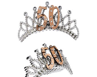 May include: A silver tiara with rhinestones and a gold 50 on top. The tiara is a birthday party accessory.