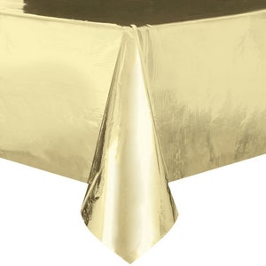 May include: A gold plastic tablecloth. The tablecloth is shiny and has a metallic finish.