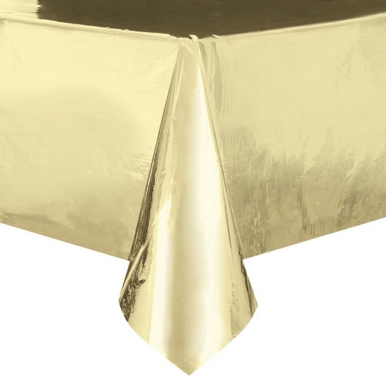 May include: A gold plastic tablecloth. The tablecloth is shiny and has a metallic finish.