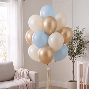 Może przedstawiać: Bukiet balonów w różnych kolorach, w tym jasnoniebieskim, kremowym i złotym. Balony są związane złotą wstążką. Balony to świąteczna dekoracja.