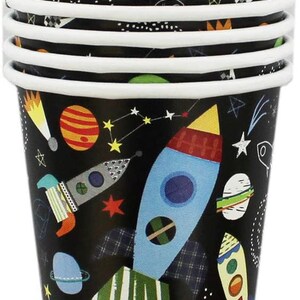 May include: A stack of 9 paper cups with a black background and a colorful space-themed design. The cups feature rockets, planets, stars, and other space-related imagery.